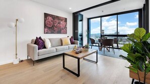Una sala moderna con sofá, mesa de centro y ventanas amplias con vistas a la ciudad.