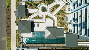 A modern building with a central courtyard, a swimming pool, and a landscaped area with trees. - 3BR Lux Beachfront Escape - Pool Gym King bed (Sunshine Coast)