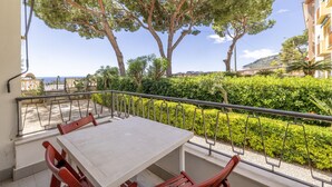 A balcony with a table and chairs, overlooking a well-maintained garden and a distant view of the sea. - Next to the Beach by Wonderful Italy (Ospedaletti)