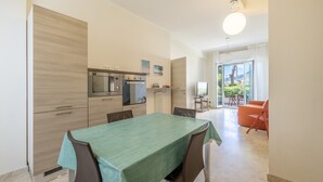 A modern kitchen with a dining area, featuring a table with chairs, a refrigerator, and a stove. - Next to the Beach by Wonderful Italy (Ospedaletti)