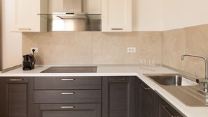 Una cocina moderna con armarios de madera oscura, un lavamanos de acero inoxidable y un salpicadero de vidrio.