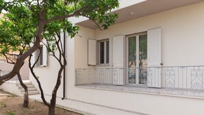 Un edificio con un balcón, un árbol en primer plano y una escalera que conduce a la entrada.
