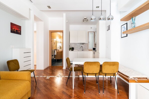 A modern apartment with a dining area, kitchen, and a hallway leading to a bathroom.