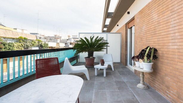 A balcony with a white table, two white chairs, a potted plant, and a brick wall. - Tina's Penthouse by Wonderful Italy (Bari)