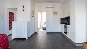 A modern kitchen with white cabinets, a black countertop, and a built-in oven. - Tina's Penthouse by Wonderful Italy (Bari)
