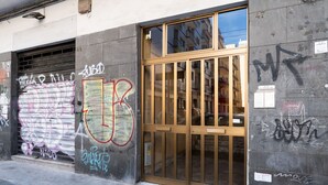 A building with a closed metal shutter door and a wooden door with glass panels. Graffiti is visible on the walls. - Gil's Penthouse by Wonderful Italy (Bari)