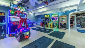An arcade with various gaming machines, including a red car-themed game and a Batman-themed machine.