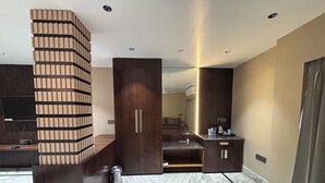 Een moderne hotelkamer met een ruime kast, een ingebouwde televisie, een vloer met marmerpatroon en een klein kitchenette.
