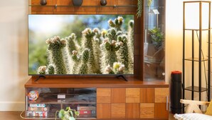 A flat-screen TV mounted on a wooden cabinet with a glass shelf below. - Work ready Mezzanine | BBQ + Pool | Pierson Street (Phoenix)
