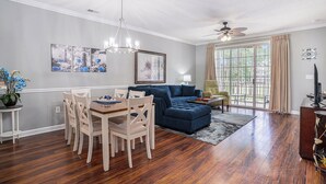 A dining area with a wooden table and chairs, a blue sofa, and a chandelier.