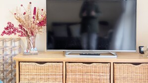 A flat-screen TV on a wooden cabinet with wicker baskets underneath.