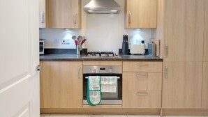A modern kitchen with wooden cabinets, a stainless steel range hood, a built-in oven, and a gas stove.