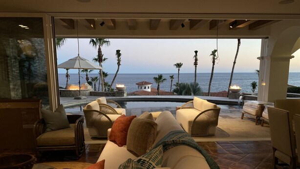 Ein großzügiger Wohnbereich mit Meerblick, ausgestattet mit Sofas und Sesseln, und ein Pool im Hintergrund.