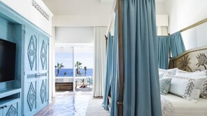 Ein Schlafzimmer mit einem großen Bett, einem Fernseher und Blick auf den Ozean.