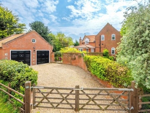 A brick house with a gravel driveway and a wooden gate. - 4 bedroom accommodation in Hanworth (Hanworth)