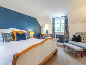 A bedroom with a large bed, a desk, a chair, and a window with curtains. - 4 bedroom accommodation in Hanworth (Hanworth)