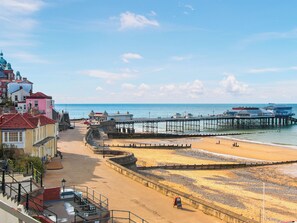 A coastal area with a beach, promenade, and pier.