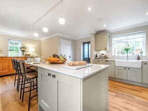A modern kitchen with a central island, wooden chairs, a dining area, and a view of the outdoors.