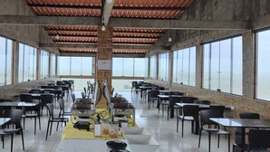 Ein Restaurant mit einer langen Theke, hohen Decken, großen Fenstern und Meerblick.