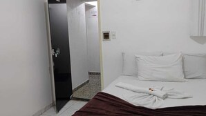 Ein Hotelzimmer mit einem Bett, einer Tür und einem kleinen Badezimmer, das durch den Durchgang sichtbar ist.