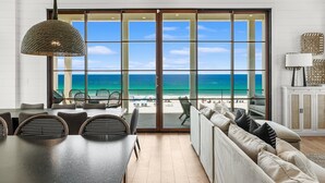 A modern living room with a large sliding glass door leading to a balcony with a view of the beach. - Gulf-Front Luxury Home w/ Panoramic Views • Private Pool • Carillon Beach (Panama City Beach)