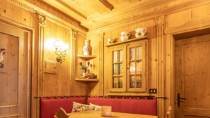 Un coin repas chaleureux, aménagé en bois, avec un banc, une table et des chaises.