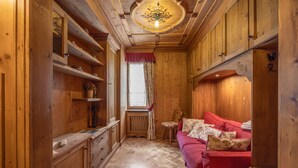 Un intérieur en bois avec un canapé rouge, des étagères en bois, un radiateur et une fenêtre avec des rideaux.