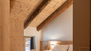 A wooden-framed bedroom with a bed, a nightstand, and a wall-mounted light. - Casa Verocip, a panoramic attic with a view of the Dolomites (Cortina d´Ampezzo)