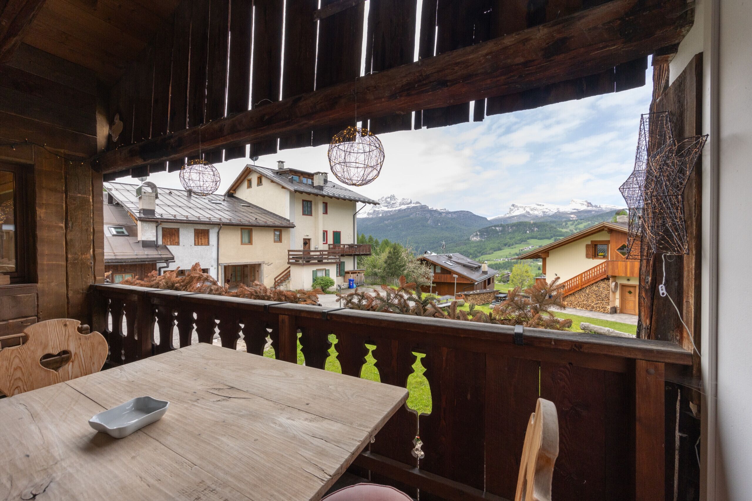 A wooden balcony with a view of houses and mountains.