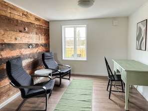 A room with a wooden wall, a window, a table, and two chairs.