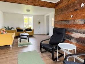 A living room with a yellow sofa, a black armchair, and a small white table.
