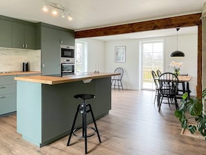 A modern kitchen with a central island, bar stools, and a dining area with chairs. - 4 Star Holiday Home in Haltorp (Halltorp)