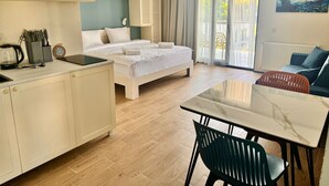 A modern hotel room with a bed, a dining table, and a kitchen area. - Terrace Kaprovan (Ureki)