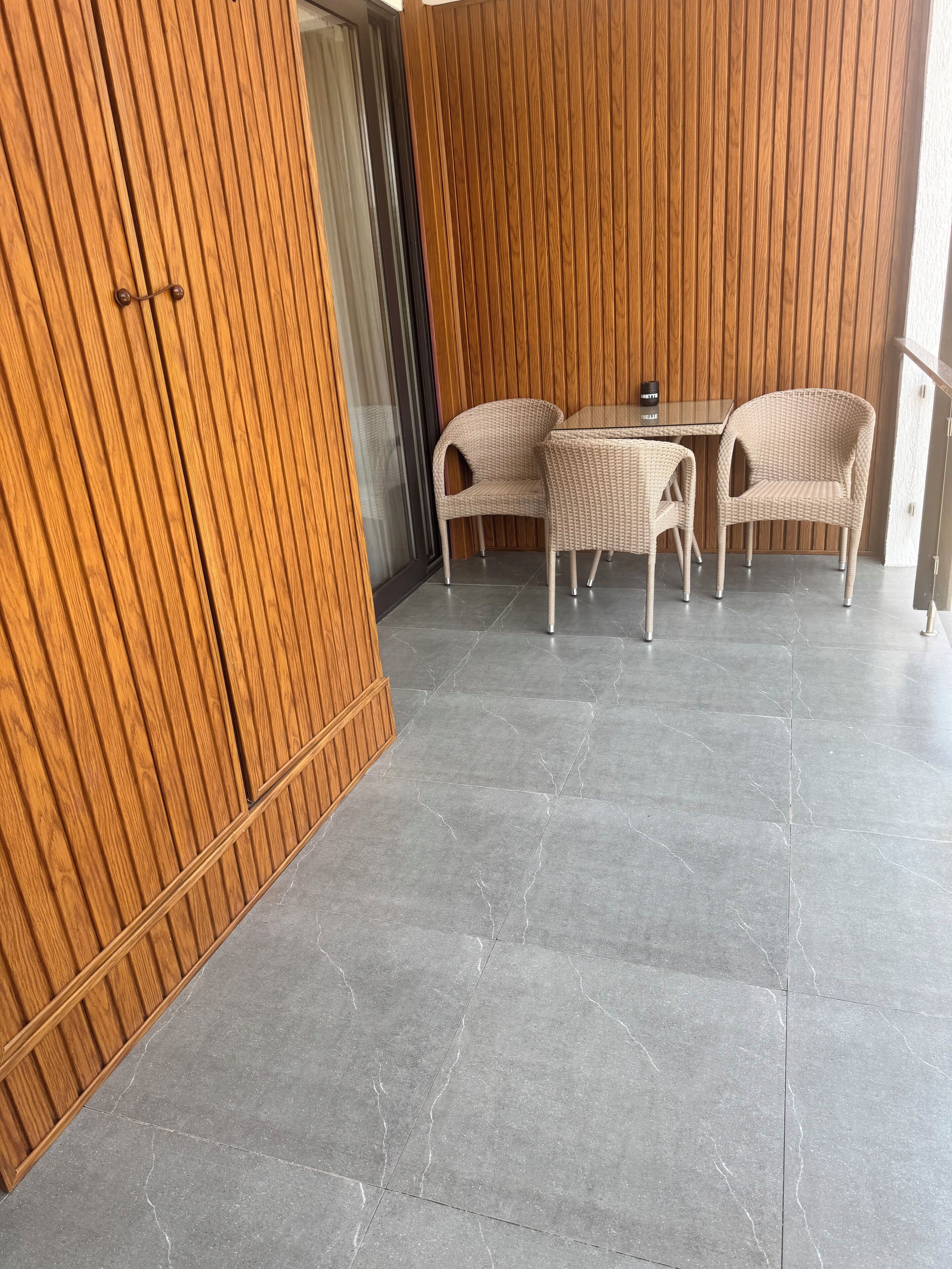 Un interior moderno con un panel de madera, una puerta de cristal y un comedor con sillas de mimbre y una mesa de cristal.