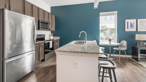 A modern kitchen with stainless steel appliances, a central island, and a window providing natural light. - Landing | Incredible 1BD, Pool, Clubhouse (Jacksonville)