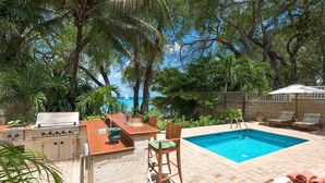An outdoor pool area with a grill and seating.