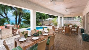 An outdoor patio with a pool, dining area, and seating.