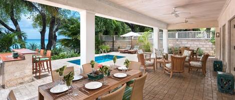 An outdoor patio with a pool, dining area, and seating.