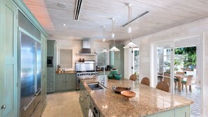 A spacious kitchen with a large island, stainless steel appliances, and pendant lighting.