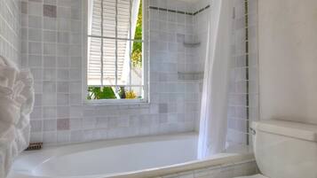 Un baño con bañera, ventana y retrete.