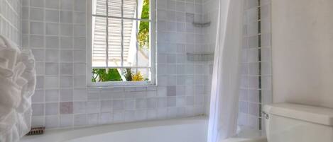 A bathroom with a bathtub, a window, and a toilet.