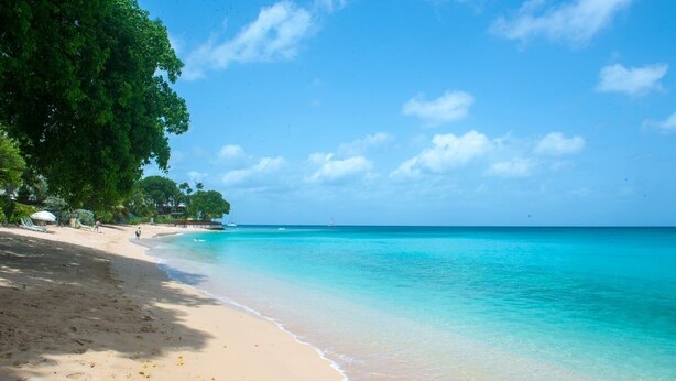A beach with clear turquoise water, a sandy shore, and lush green trees. - Waverly House 3 Bedroom Townhouse (Bowling Alley Hill)