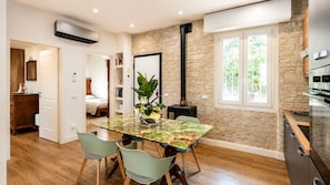 A modern kitchen with a stone wall, a dining area with a glass table, and a visible stove. - Allegra Villa Apt 1 - House in the Woods (Lombardia)