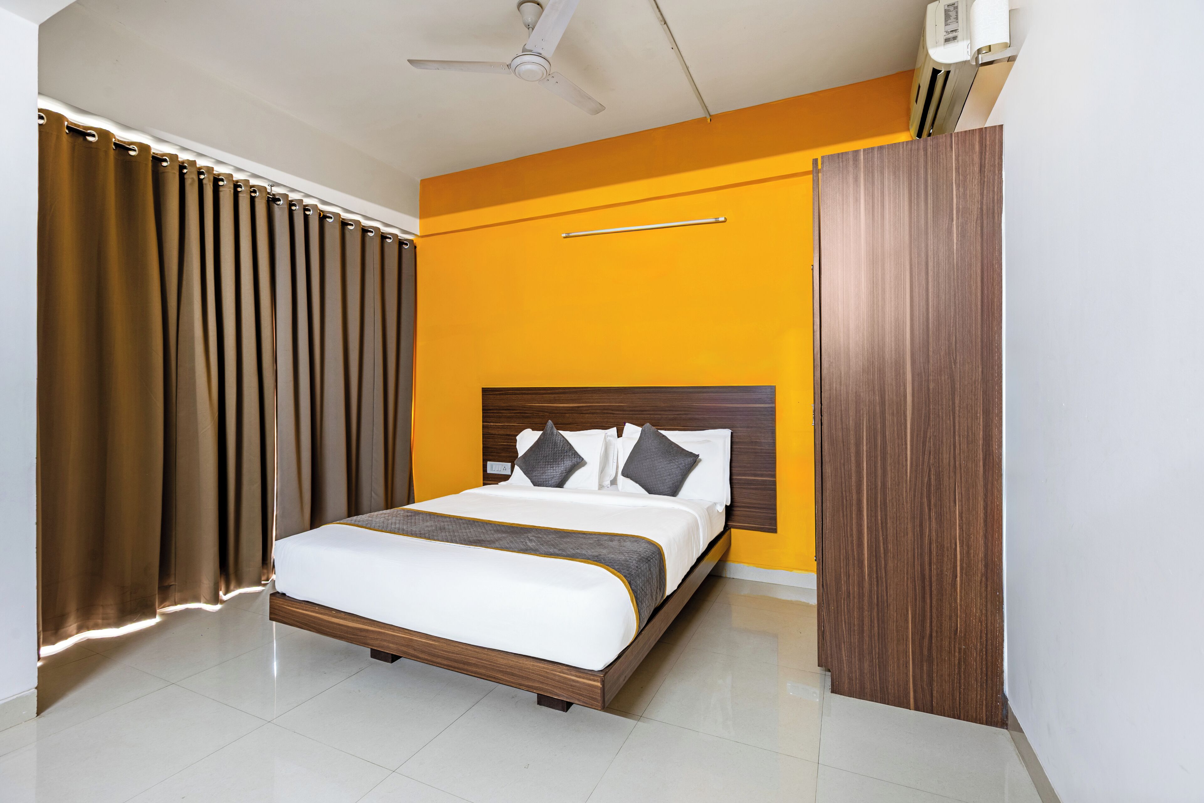 Une chambre moderne avec un lit, des rideaux, un ventilateur de plafond et un appareil de climatisation.