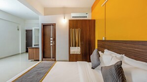 A hotel room with a bed, a wooden wardrobe, a desk, and a bathroom. - Hotel Acacia Yelahanka (Bengaluru)