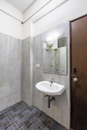 A bathroom with a white sink, a mirror, and a shower area.