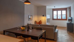 Uma sala de estar moderna com uma mesa de jantar, sofá e uma janela grande com vista.