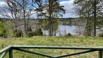A view of a lake surrounded by trees and a green wooden fence in the foreground.