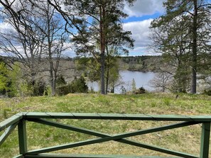 A view of a lake surrounded by trees and a green wooden fence in the foreground. - 7 Person Holiday Home in Bjornlunda (Björnlunda)