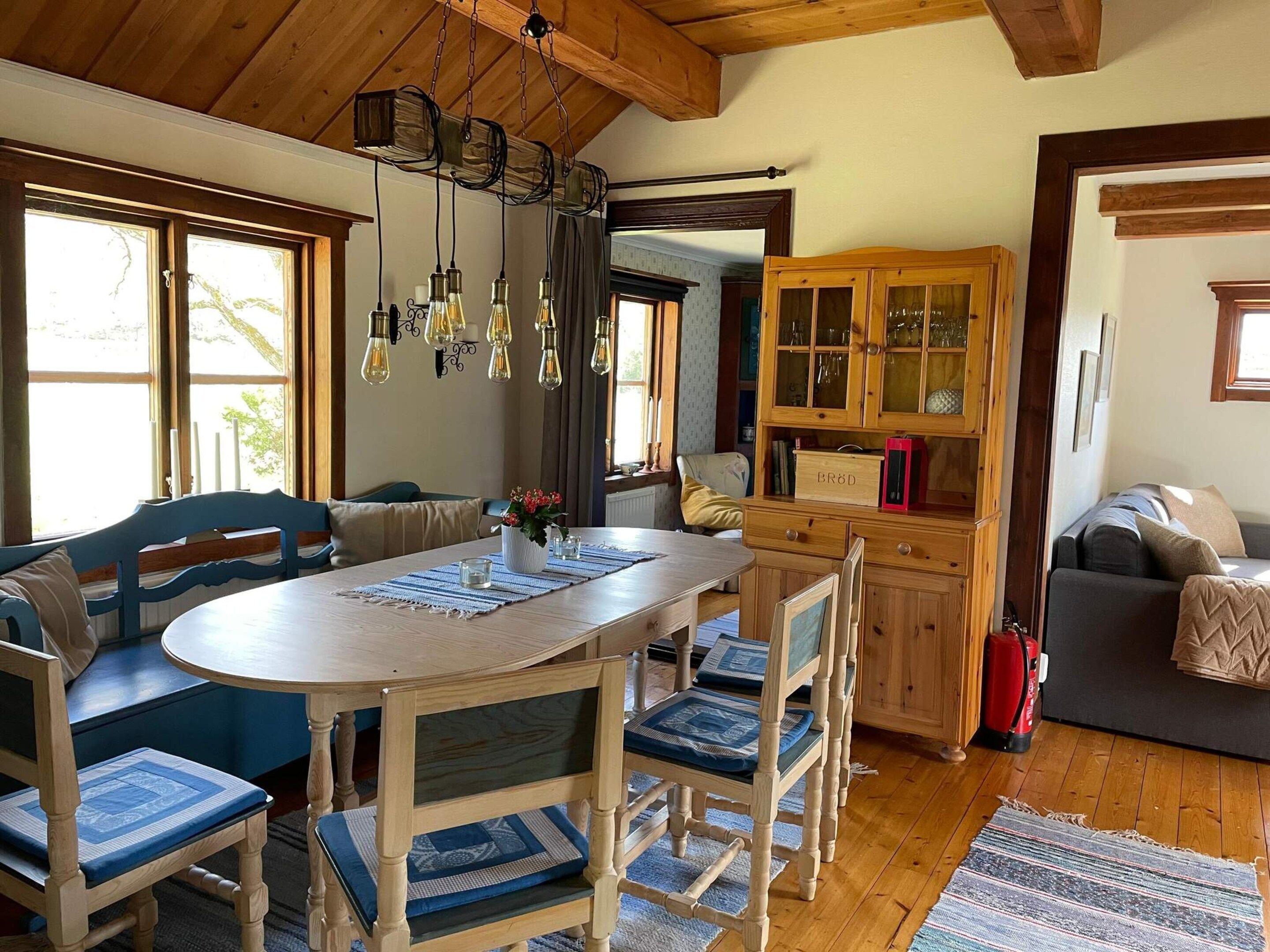A dining area with a wooden table, blue upholstered chairs, and hanging light fixtures.